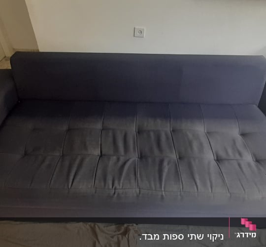 ספה כהה עם כתמים על המושב, מונחת על שטיח בהיר